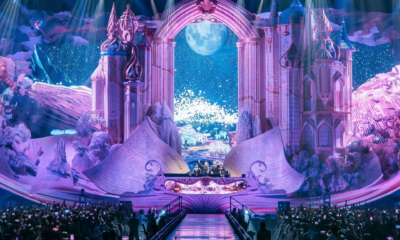 The Magic of Tomorrowland stage in Shanghai featuring a large fantasy castle design, moonlit backdrop, giant open books and a packed indoor audience.