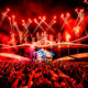 Red fireworks and pyrotechnics exploding above the UNTOLD Mainstage as the crowd raises their hands and phones