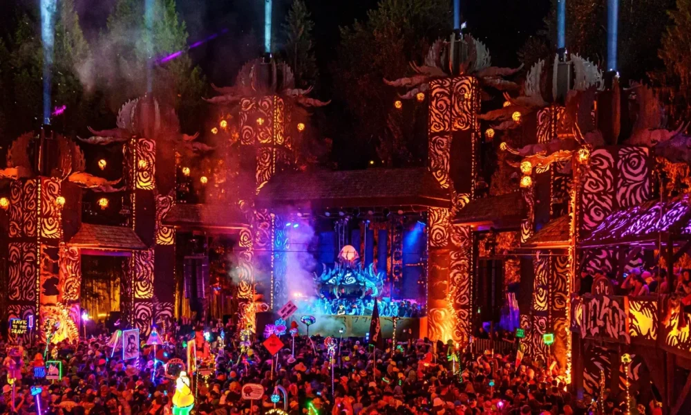 Crowd gathered in front of the illuminated Pagoda Stage at Shambhala Music Festival 2026, with colourful totems and lights throughout the forest