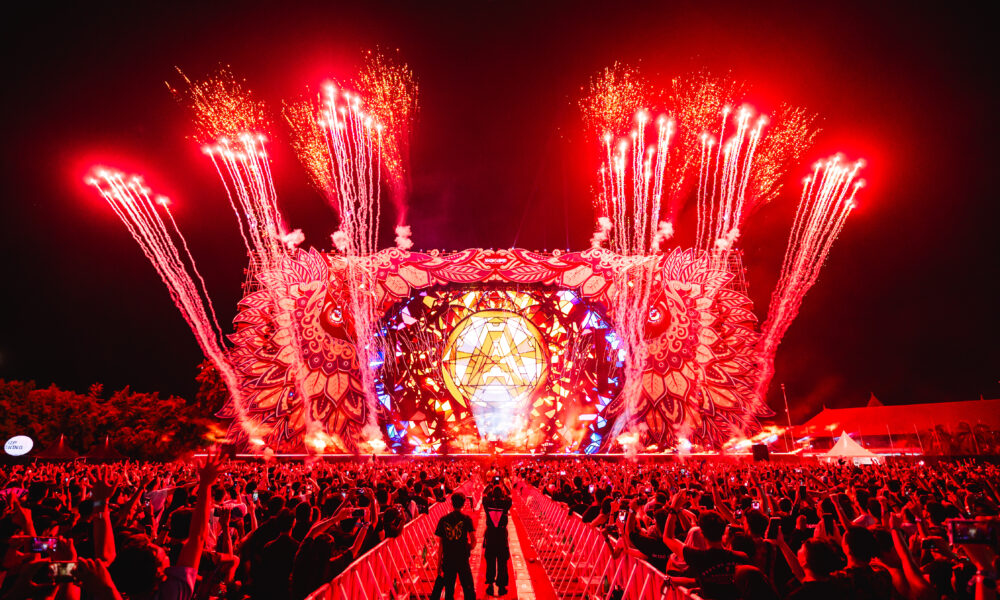 Red fireworks and pyrotechnics exploding above the Djakarta Warehouse Project (DWP) mainstage as the crowd raises their hands