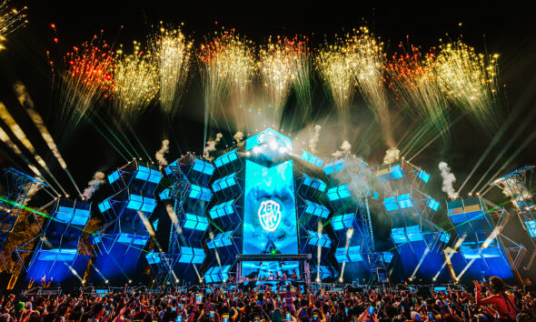 Crowd filming fireworks above a blue-lit stage at EDC Thailand in Phuket