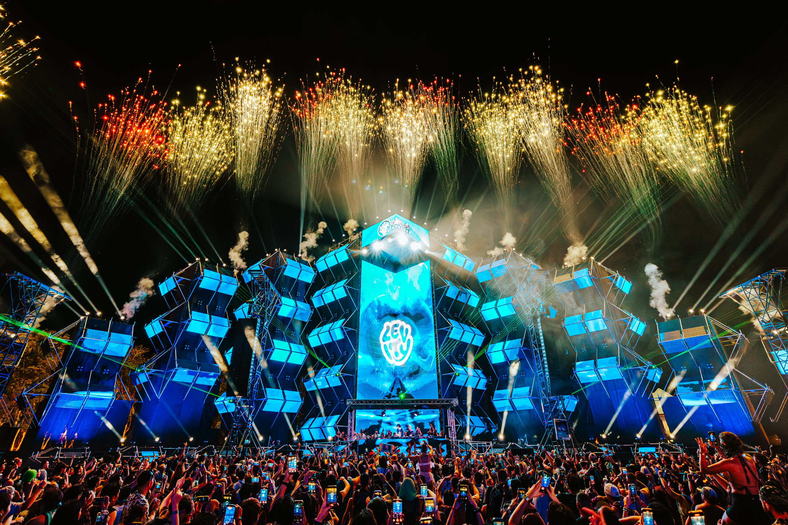 Crowd filming fireworks above a blue-lit stage at EDC Thailand in Phuket