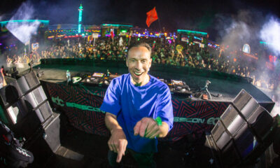 DJ Isaac smiling and pointing at the camera on the Basscon stage at EDC with a packed crowd behind him