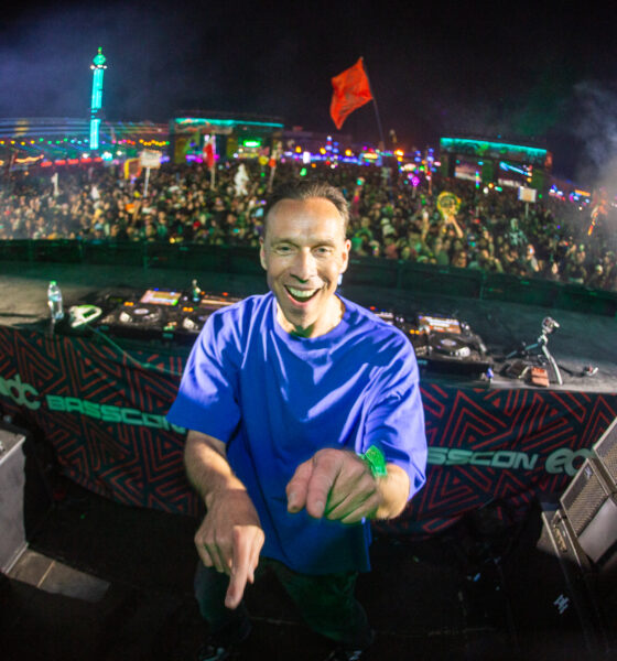 DJ Isaac smiling and pointing at the camera on the Basscon stage at EDC with a packed crowd behind him