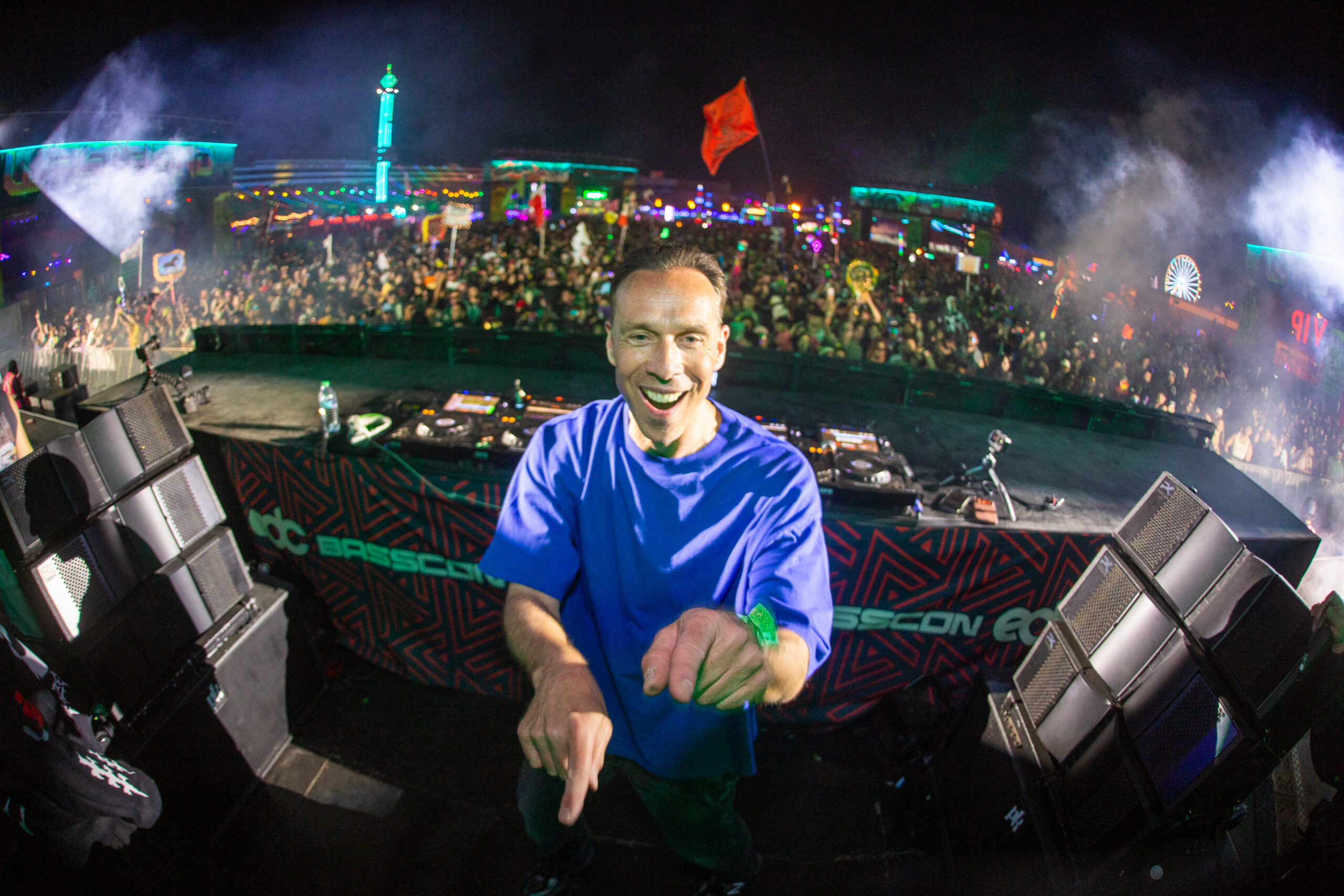 DJ Isaac smiling and pointing at the camera on the Basscon stage at EDC with a packed crowd behind him