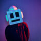 MEETCH wearing his LED-lit robot helmet and a red and black shirt against a purple backdrop