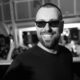 Black and white photo of Sebastian Ingrosso smiling and reaching toward the camera in front of a crowd