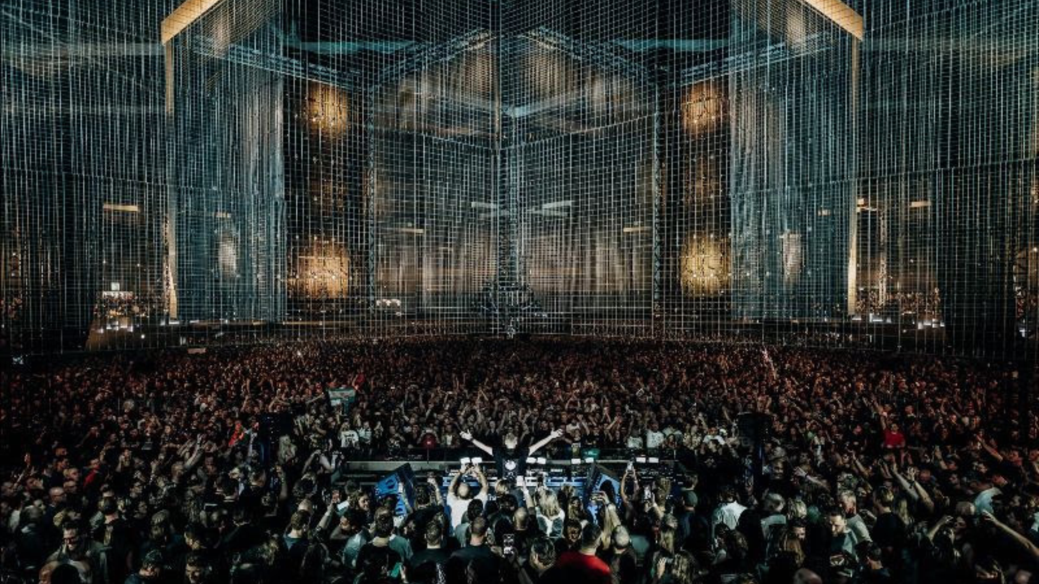 Armin van Buuren performing in front of a large crowd beneath the stage production at A State of Trance