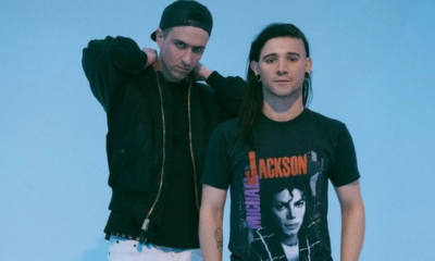 Boys Noize and Skrillex posing together against a light blue background