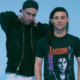 Boys Noize and Skrillex posing together against a light blue background