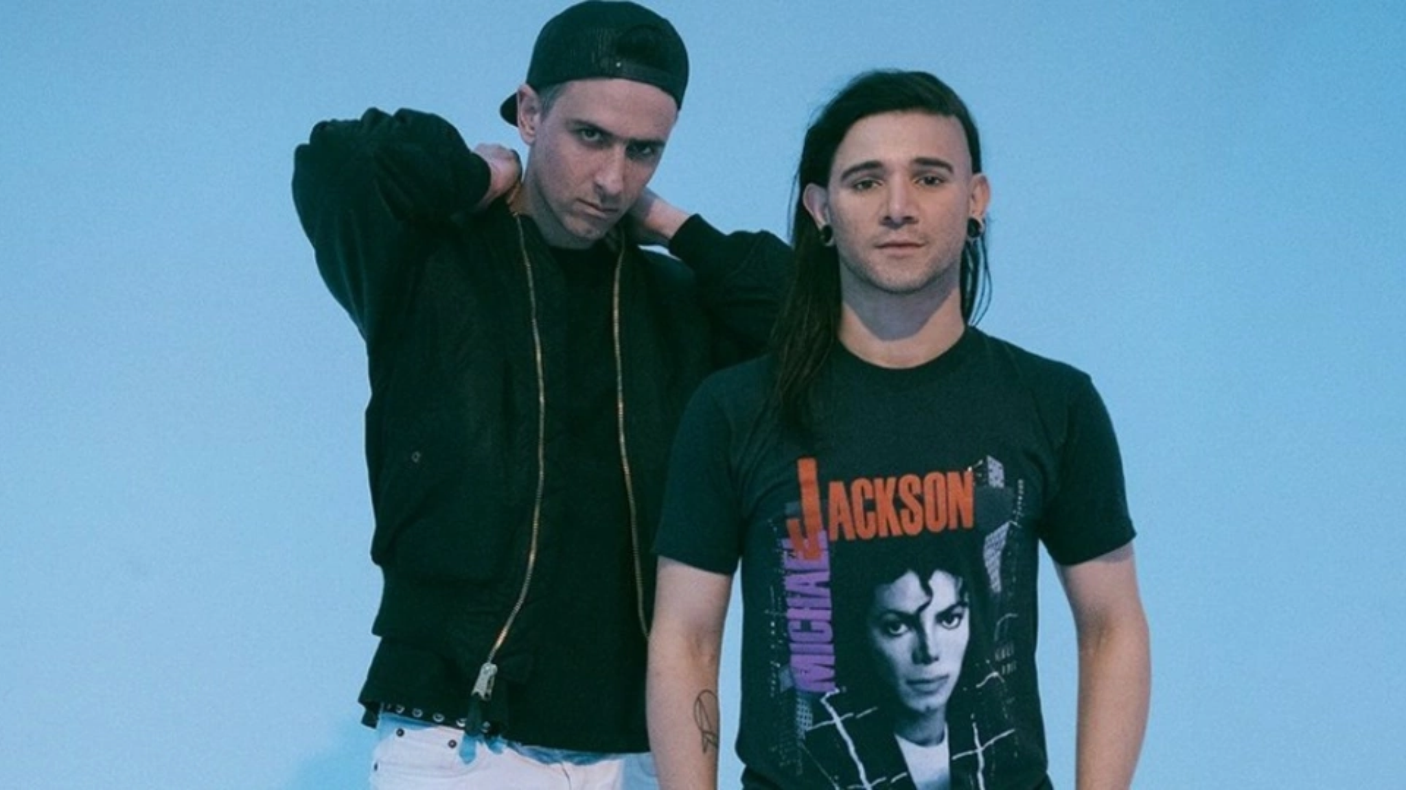 Boys Noize and Skrillex posing together against a light blue background