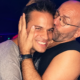Argy smiling as Sven Väth kisses him on the cheek inside a nightclub