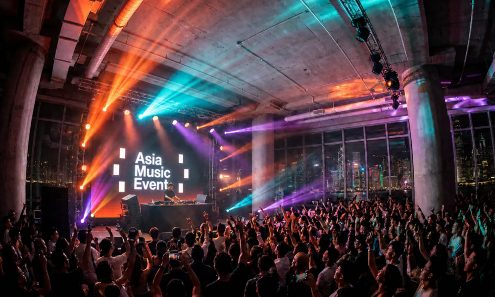 A DJ performs at Asia Music Event in Hong Kong as a large crowd gathers in front of the stage with the Asia Music Event logo on screen.