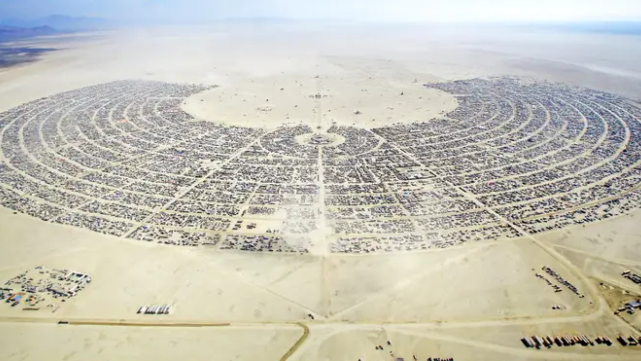 Aerial view of Black Rock City in Nevada’s Black Rock Desert, showing the large semicircular layout of Burning Man and its surrounding camps.