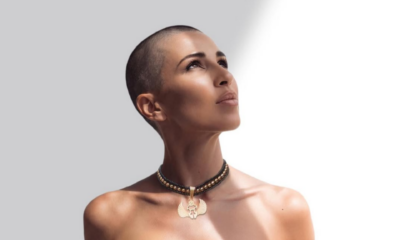 Portrait of B Jones with a shaved head looking upward against a light grey and white background.