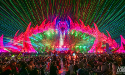 Lost Lands stage illuminated by colorful lasers as a large crowd watches the performance at Legend Valley