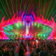 Lost Lands stage illuminated by colorful lasers as a large crowd watches the performance at Legend Valley
