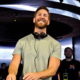 Calvin Harris smiling behind the decks with headphones around his neck during a live performance
