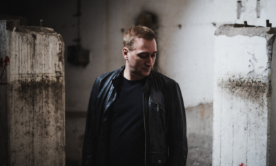 Paul van Dyk wearing a black leather jacket inside an industrial concrete setting ahead of The Essence of Acid live show.