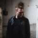 Paul van Dyk wearing a black leather jacket inside an industrial concrete setting ahead of The Essence of Acid live show.