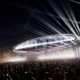Head Trip stage concept at Empire Polo Club with a large suspended oval structure, bright white beams and a crowd below