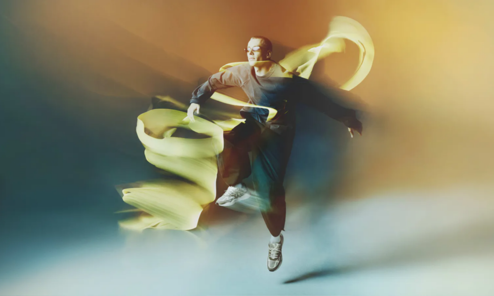Lost Frequencies wearing Tomorrowland WR1 sneakers in the official campaign, surrounded by flowing yellow fabric.