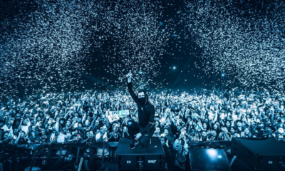 Alan Walker posing in front of a large crowd during a live performance as confetti falls around the venue