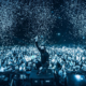 Alan Walker posing in front of a large crowd during a live performance as confetti falls around the venue