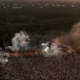 Aerial view of Zamna Tulum surrounded by jungle, with a large crowd, stage production, smoke and lighting at sunset