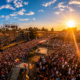 A large crowd gathers in front of a stage at EXIT Festival in Serbia during a sunset performance.
