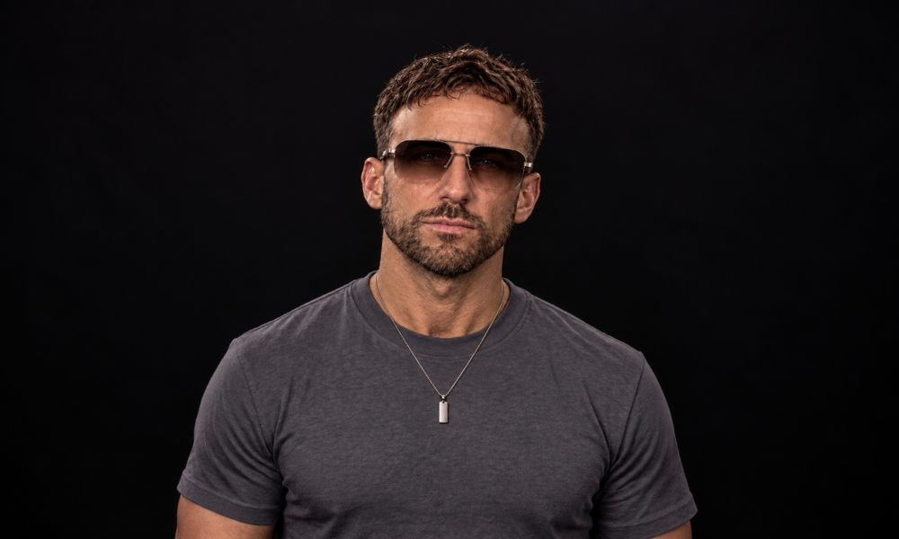 Promotional portrait of Two Phased producer Stephen wearing sunglasses against a dark background.