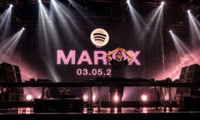 Martin Garrix makes a heart gesture during a performance beneath a Spotify logo and Marty album announcement backdrop.