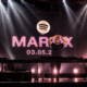Martin Garrix makes a heart gesture during a performance beneath a Spotify logo and Marty album announcement backdrop.