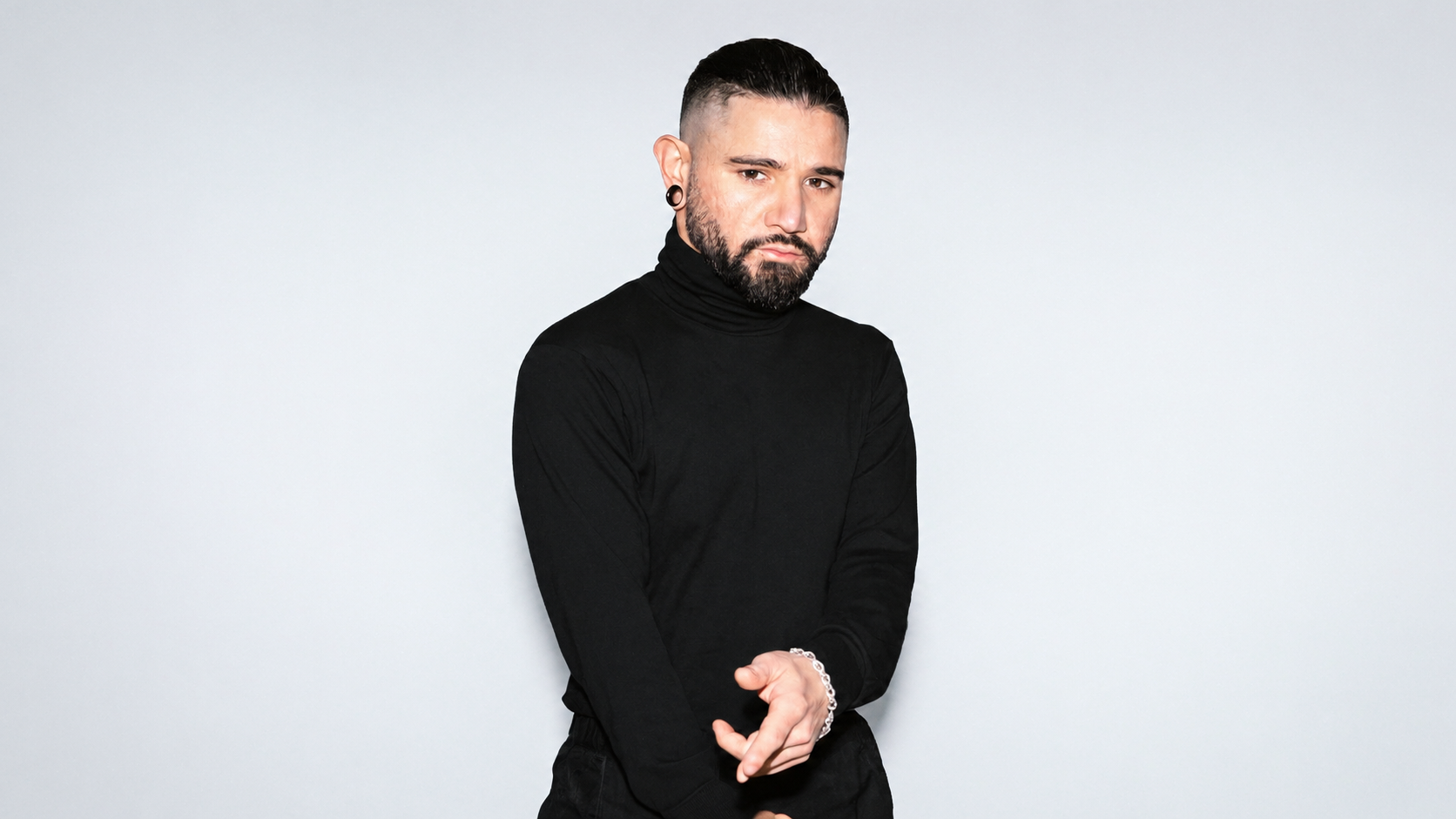 Skrillex wearing a black turtleneck in a studio portrait.