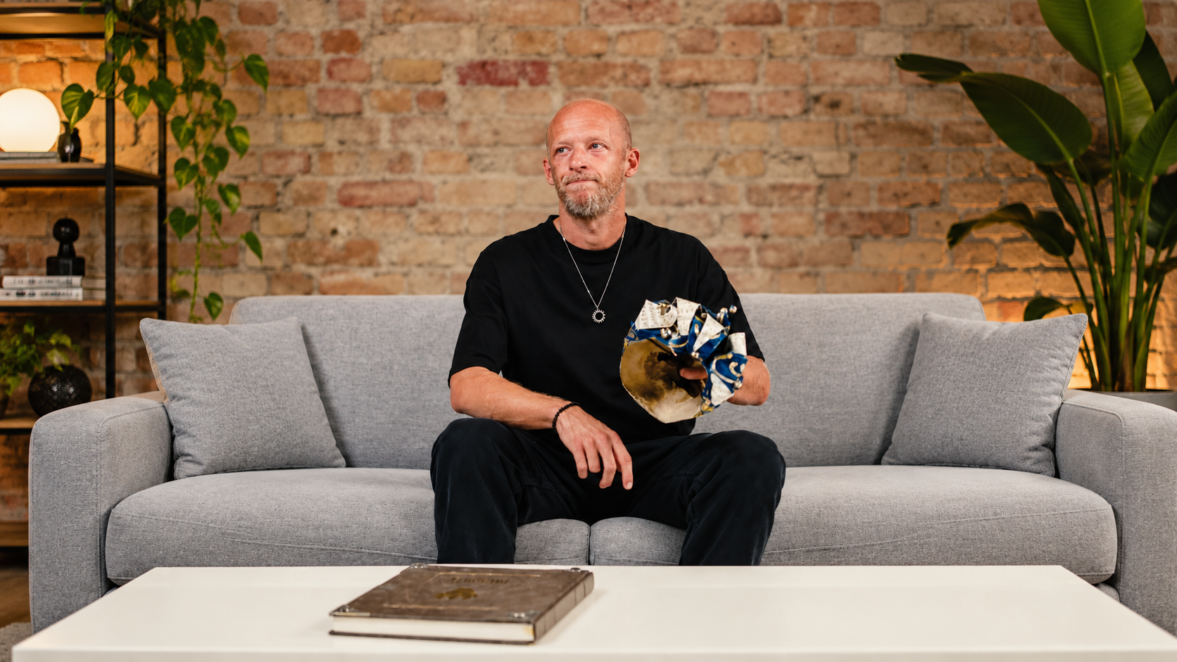High-Tech Minimal DJ Boris Brejcha sits on a sofa holding his distinctive Joker mask during an announcement about his retirement and final tour.
