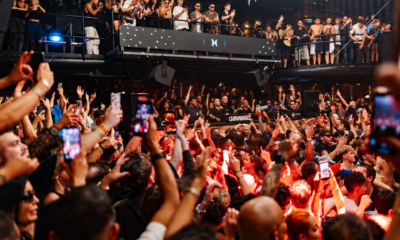 A crowded dancefloor at Amnesia Ibiza during the Metamorfosi 2026 closing, with the DJ booth surrounded by attendees under red lighting.