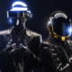 Daft Punk wearing their robot helmets and black sequined suits in a promotional photo