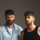 Promotional portrait for The Chainsmokers showing Alex and Drew posing against a dark studio background