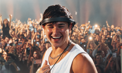 John Summit smiling during a live performance with a large crowd behind him