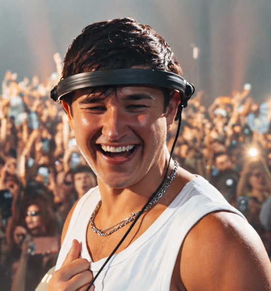 John Summit smiling during a live performance with a large crowd behind him