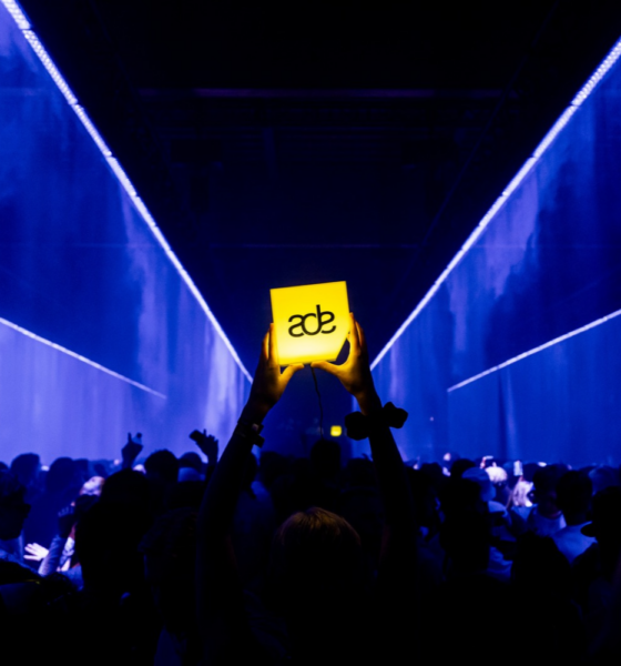 Crowd at Amsterdam Dance Event holding an illuminated ADE sign during a live electronic music event