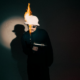 REYUS wearing sunglasses and a white hat with flames rising above it during a promotional shoot