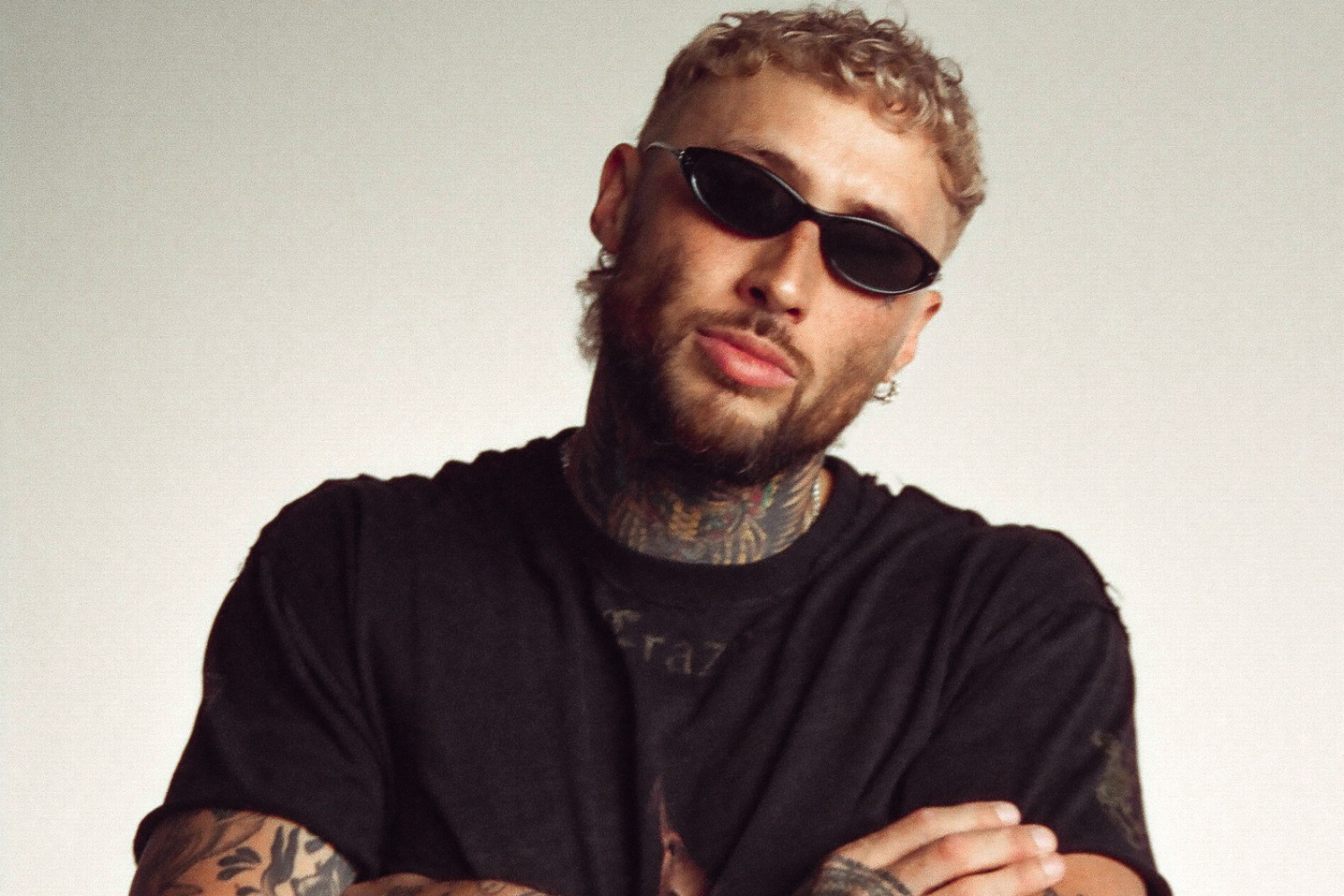 Lance Savali wearing black sunglasses and a black shirt in a promotional portrait for ‘All I See’