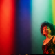 Annie Mac performing on stage under red, blue, green and yellow lighting