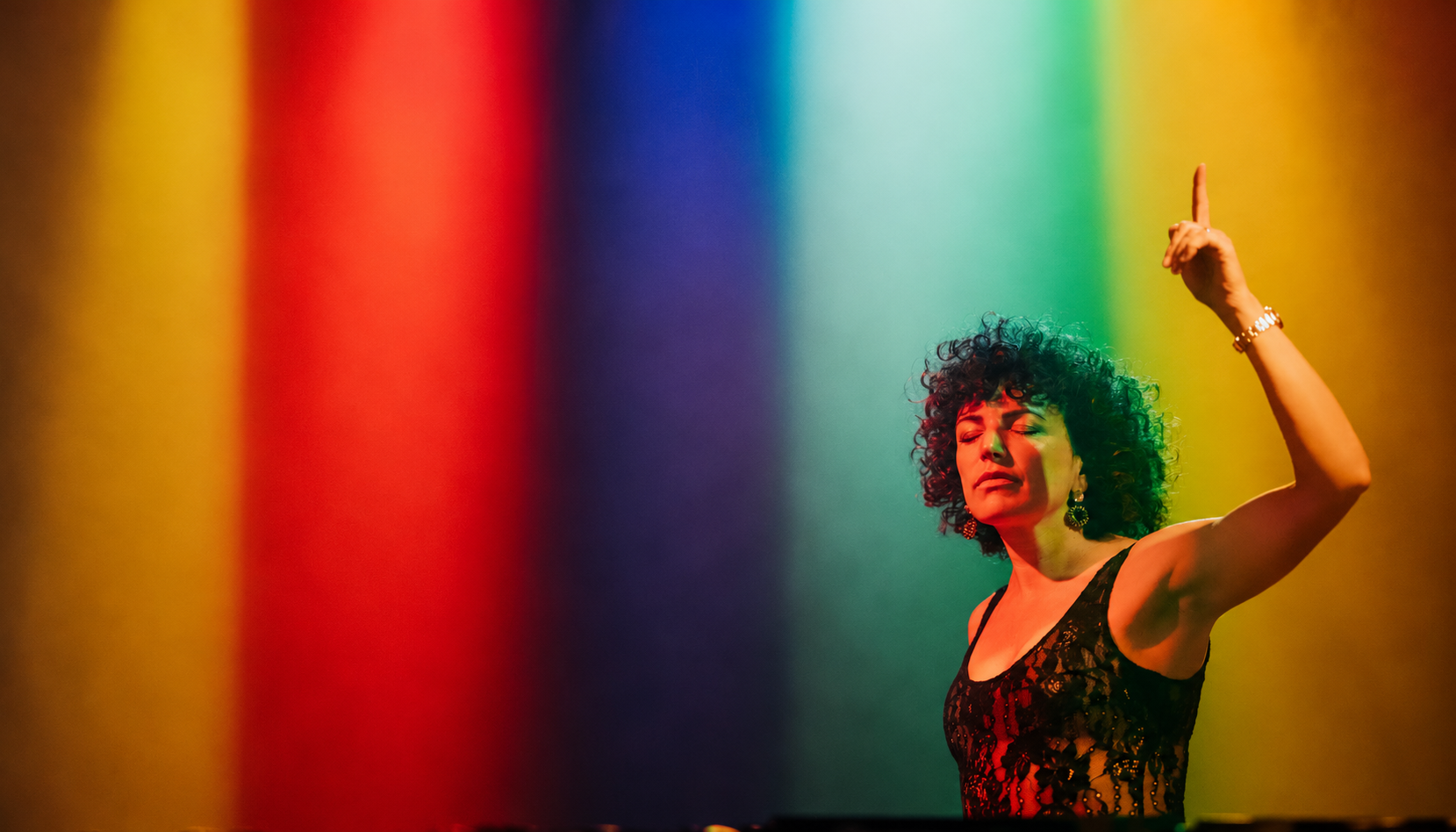 Annie Mac performing on stage under red, blue, green and yellow lighting