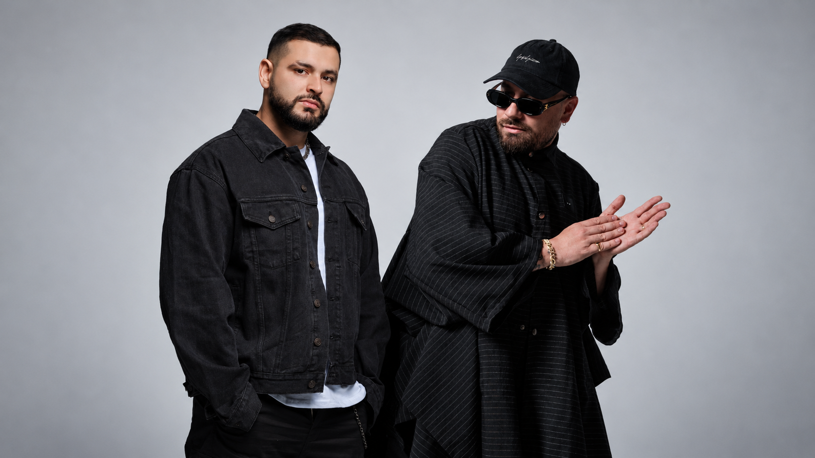 GROSSOMODDO and MOSKA posing together in black outfits against a light grey studio background
