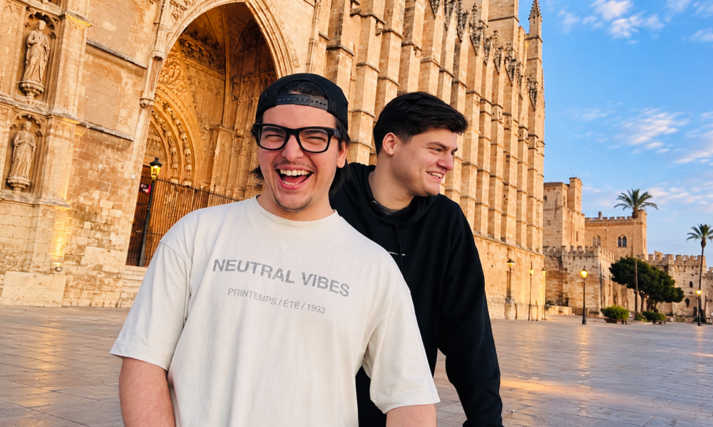 Chris Candela and Bauti Tesei smiling together outside a historic building in Mallorca