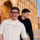 Chris Candela and Bauti Tesei smiling together outside a historic building in Mallorca