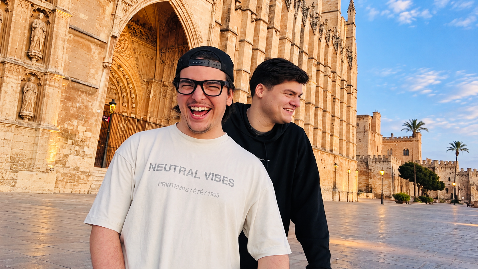 Chris Candela and Bauti Tesei smiling together outside a historic building in Mallorca