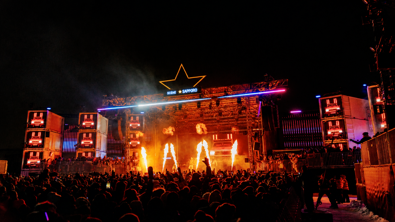 Crowd watching the Sapporo Stage with flames and red lighting during Igloofest at Montréal’s Old Port